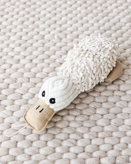 Small dog holding platypus plush toy, perfect for chew and cuddle.