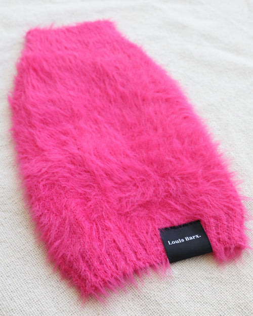 Fluffy hot pink dog sweater on white background. French bulldog pink sweater.