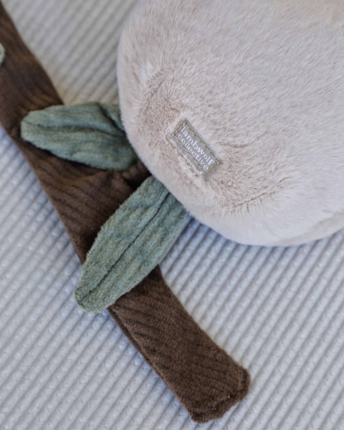 closeup of fuzzy peach dog toy with two peaches on brown corduroy branch with treat pockets  
