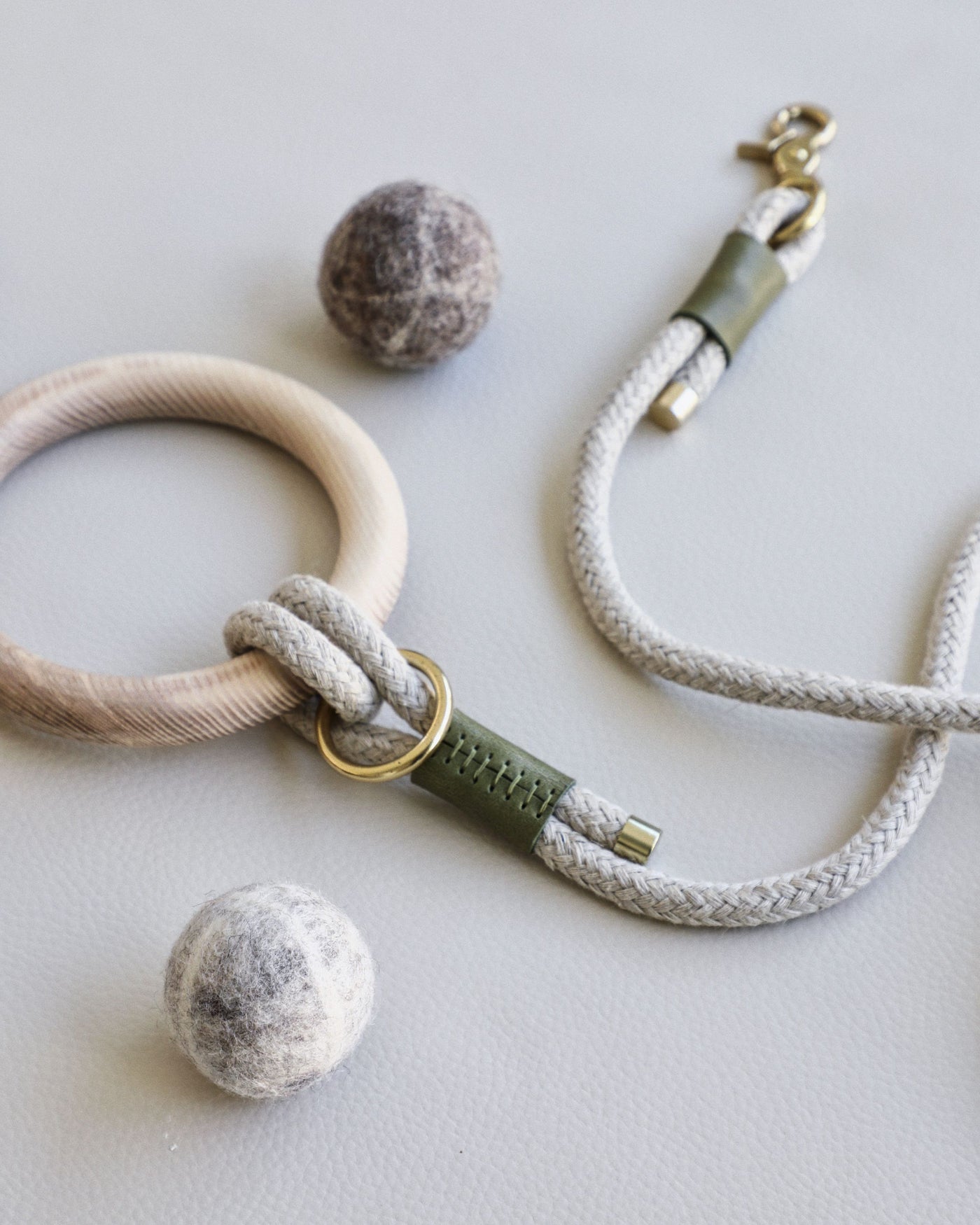 Rope leash connected to round dowel with green leather accents and gold hardware