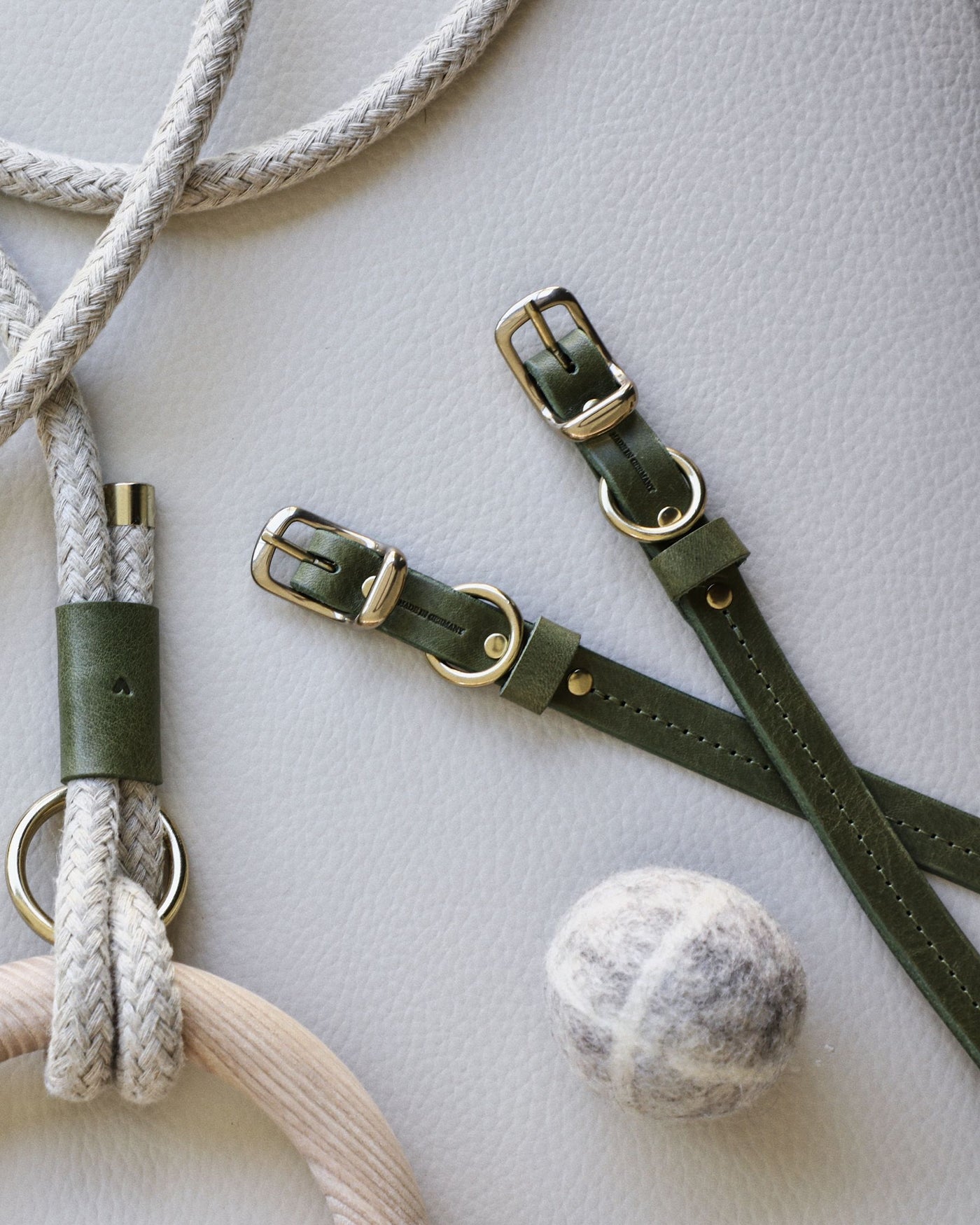 Green leather collar with brass hardware. Wood dowel rope leash also pictured as well as wool dog ball toy