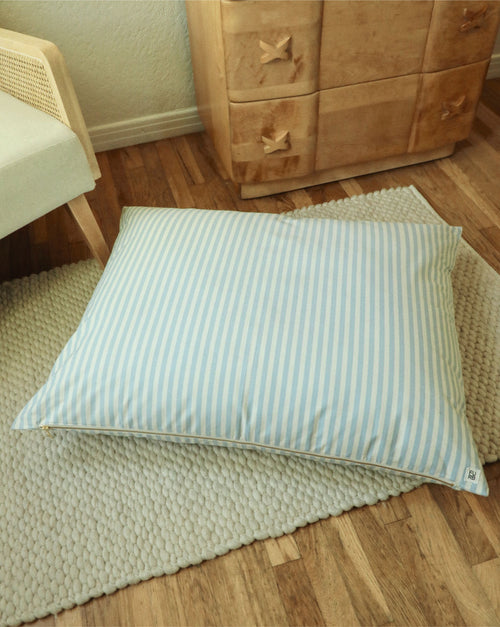 Dog enjoying Capri blue striped bed, highlighting soft interior and durable striped exterior.