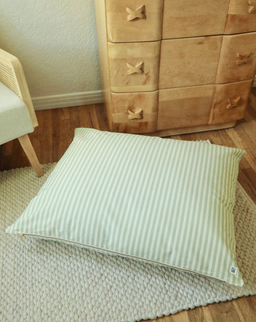 Cozy dog lying in green striped bed, showing comfort and modern pet style.