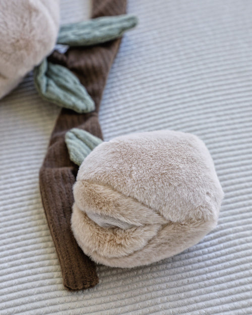 Close-up of Peachy Keen Plush Dog Toy with two peaches and treat pockets on brown corduroy branch.