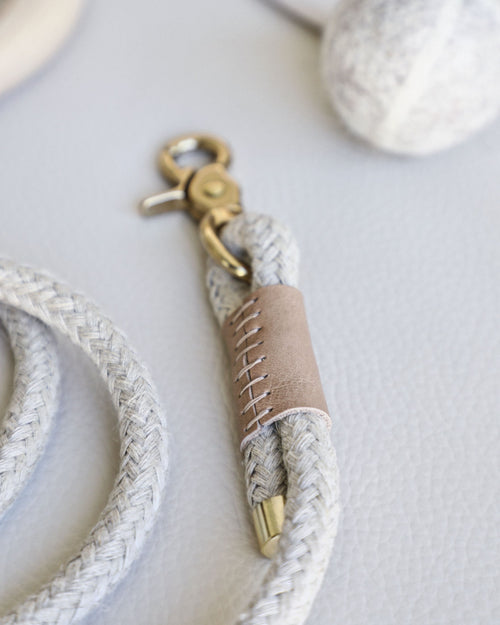 Rope leash connected to round dowel with taupe leather accents and gold hardware