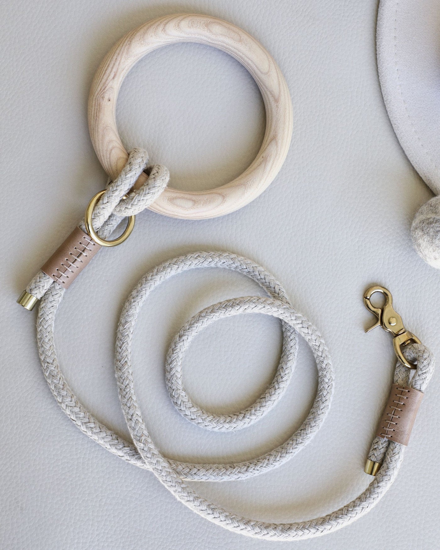 Rope leash connected to round dowel with taupe leather accents and gold hardware