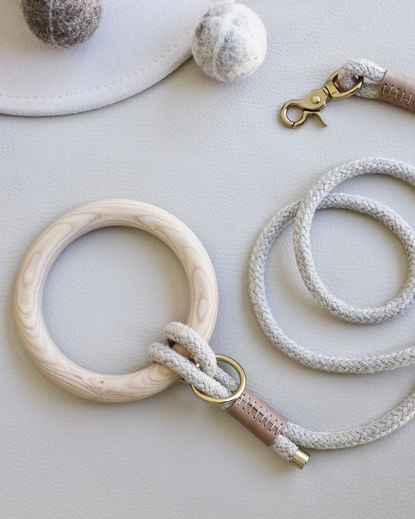 Rope leash connected to round dowel with taupe leather accents and gold hardware