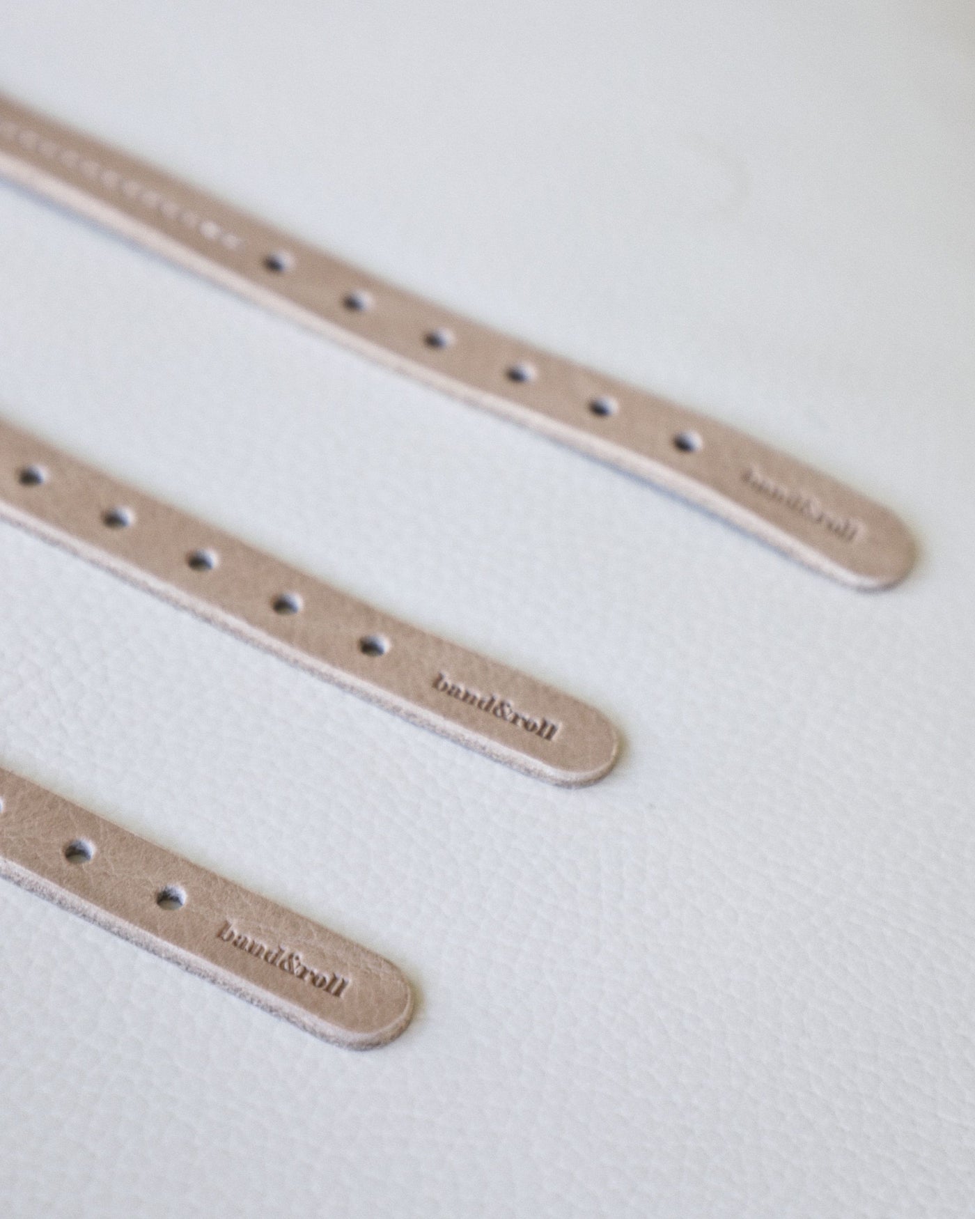 Close up of embossed logo on taupe leather dog collars