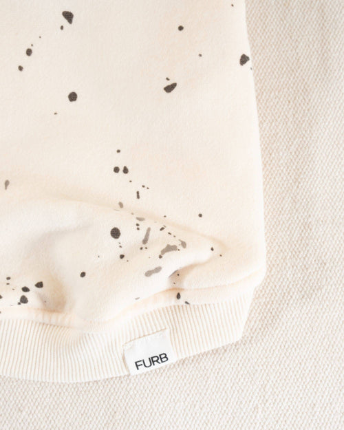 A fashionable ivory hoodie for small to medium dogs, featuring a bold paint splatter design.