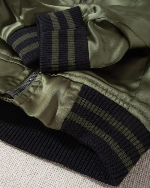 A modern take on a retro classic. Buttery-soft olive green satin practically melts over your pup, with ribbed cuffs and hem, detailed with coordinating green and black stripes. Accented with a chic pewter O-ring pull. . Frenchie bomber jacket. 