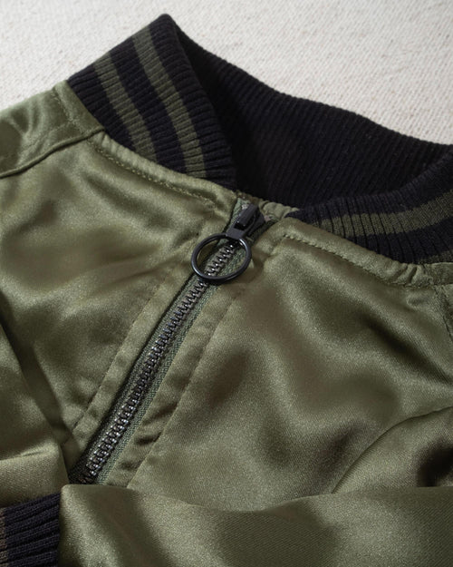 A modern take on a retro classic. Buttery-soft olive green satin practically melts over your pup, with ribbed cuffs and hem, detailed with coordinating green and black stripes. Accented with a chic pewter O-ring pull. . Yorkie bomber jacket. 